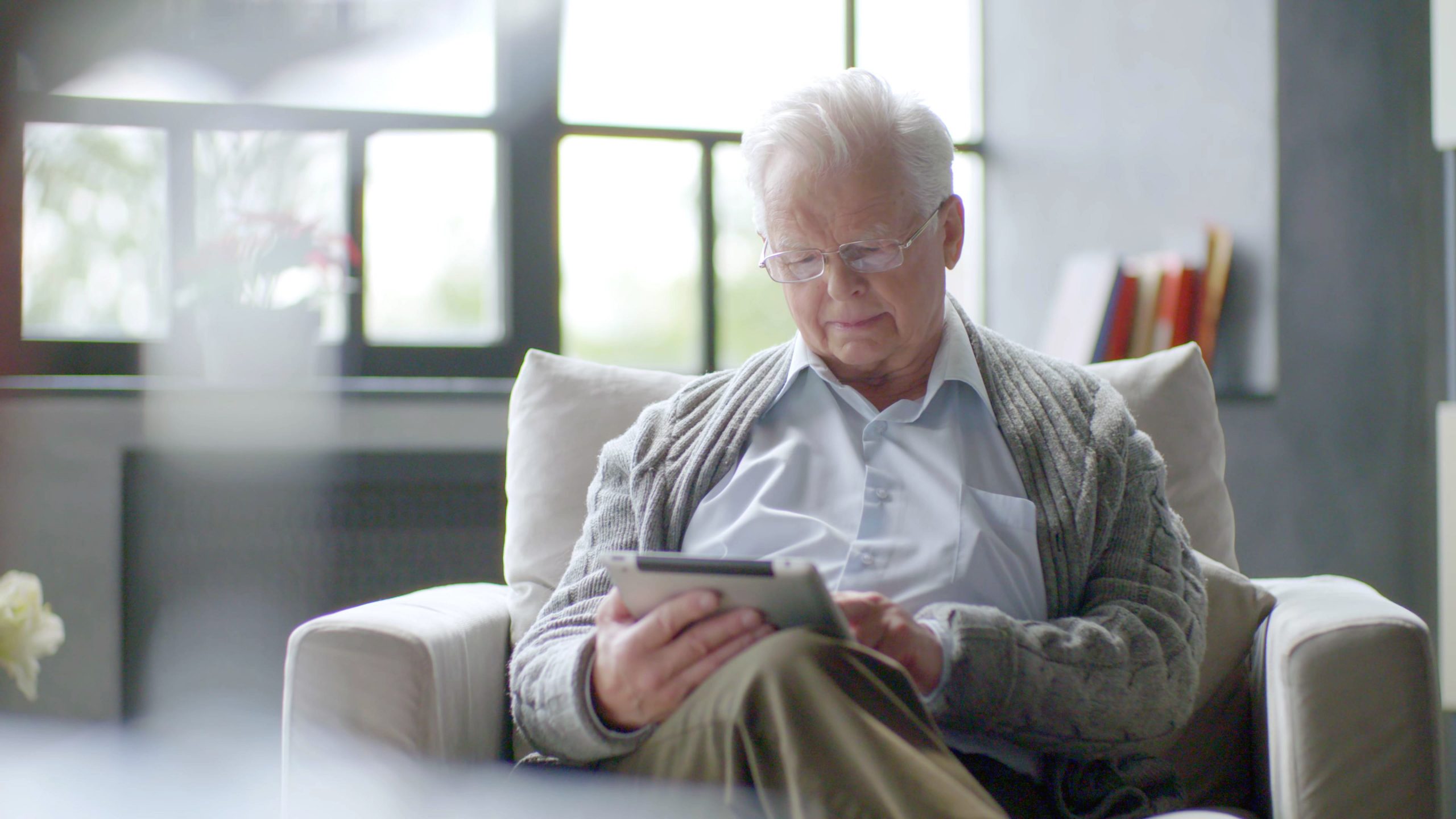 Homme senior utilisant une tablette numérique assis sur le canapé à la maison